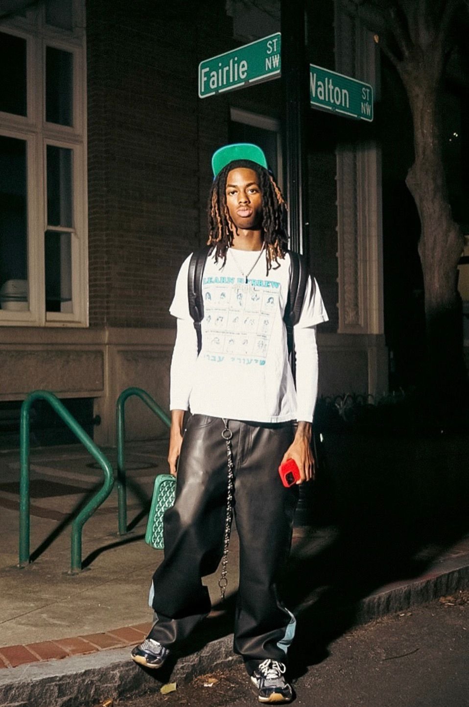 Graphic tee and leather pants on a downtown corner at night